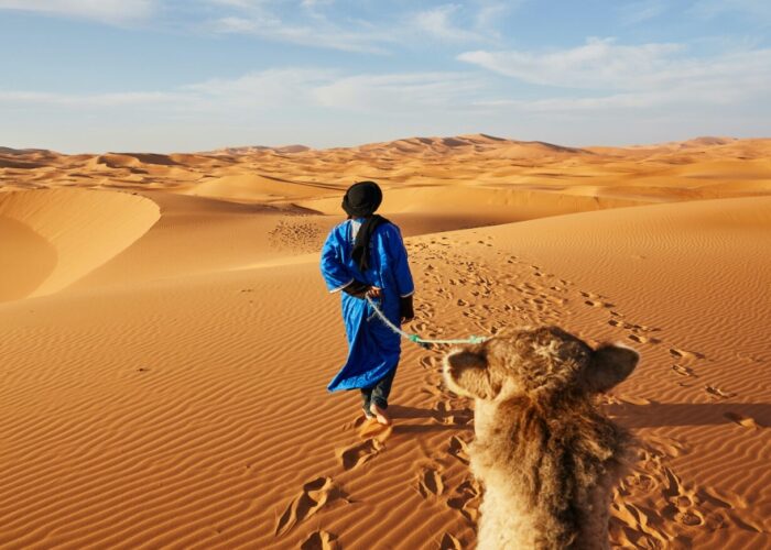 Hombre del desierto conduciendo un camello en el desierto de Merzouga durante nuestro viaje de 2 días desde Errachidia.