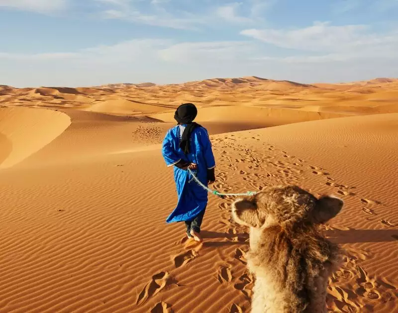 Desert man driving a camel in Merzouga desert during our 2 day tour from Errachidia.
