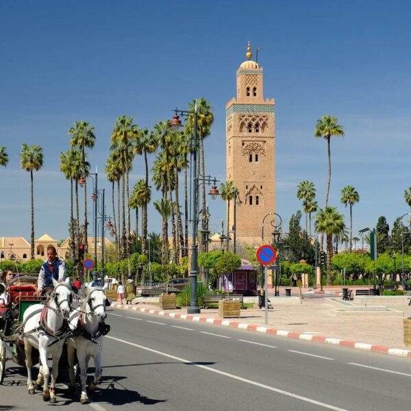 Una persona dando un paseo a caballo en Marrakech con la mezquita detrás.