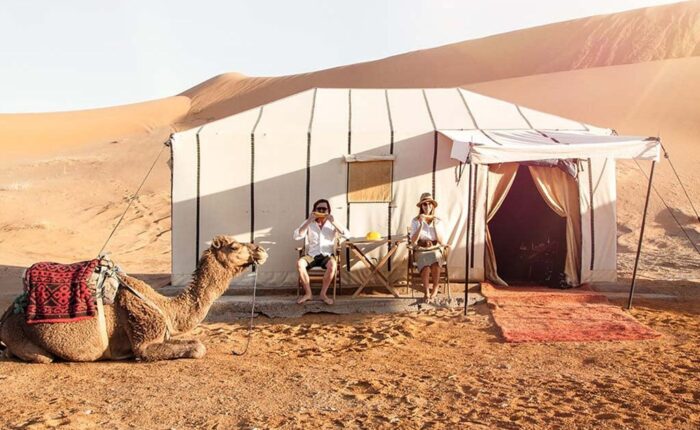 Dos personas y un camello durante el viaje de 4 días de Ouarzazate a Marrakech por el desierto