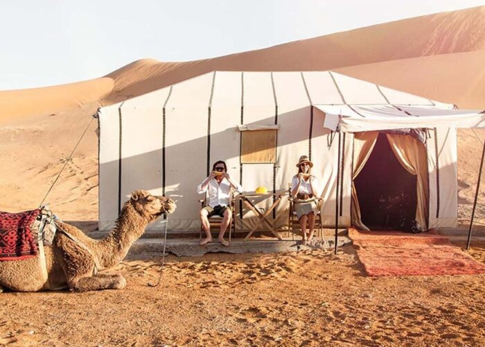 Dos personas y un camello durante el viaje de 4 días de Ouarzazate a Marrakech por el desierto