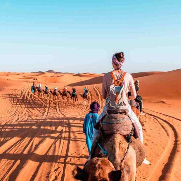 Turisti a cavallo di cammelli nel deserto di Merzouga durante il tour di 2 giorni da Fes.