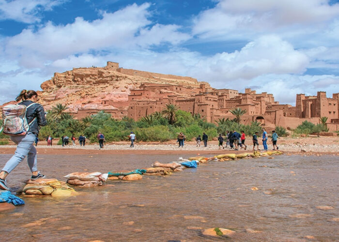 Una donna attraversa il fiume verso la Kasbah di Ait Benhaddou durante il tour di 3 giorni da Ouarzazate a Marrakech.