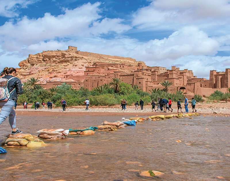 A woman crossing the river to the Kasbah of Ait Benhaddou during the 3-day tour from Ouarzazate to Marrakech.