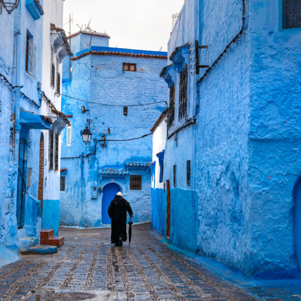 An old man walking the blue streets of Chefchaouen.