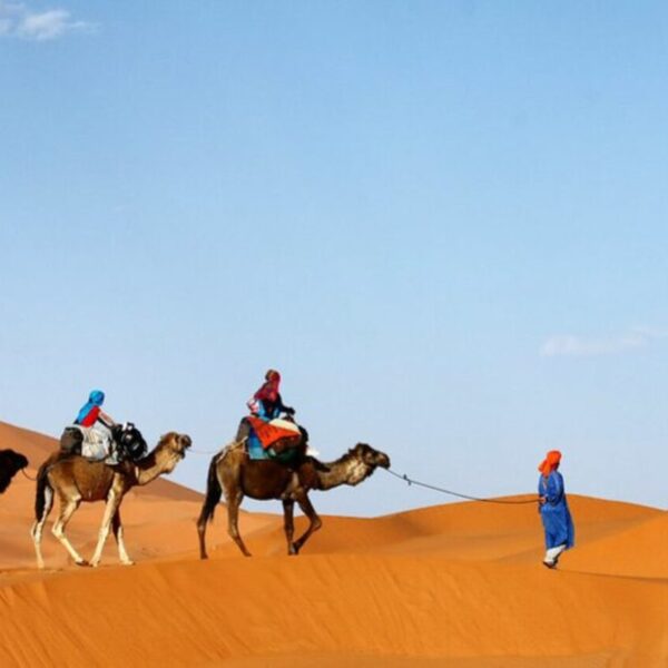 Viajeros en camello por el desierto de Merzouga durante el viaje de 11 días por el Sáhara marroquí desde Casablanca.