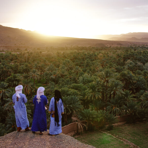 3 marroquíes contemplando la puesta de sol sobre el valle.