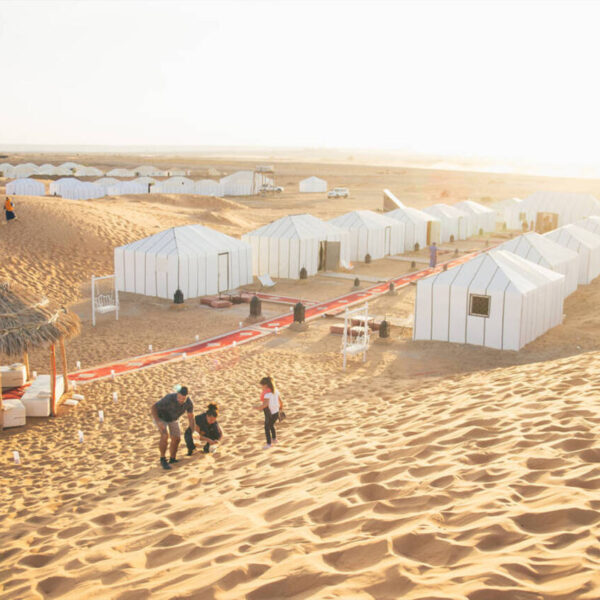 Un campamento en el desierto de Merzouga con alfombras rojas.