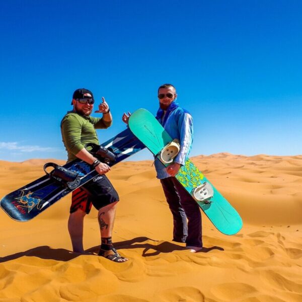 Dos tipos con tablas de sandboard en el desierto de Merzouga.