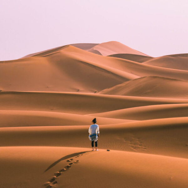 A woman standing on a sand dune in Merzouga during the 8-day Moroccan journey from Tangier.