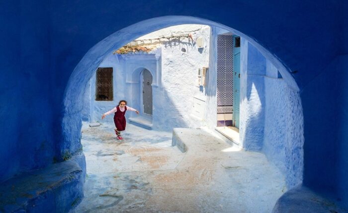 Una ragazza che cammina per le strade blu durante il tour di 2 giorni da Tangeri a Chefchaouen.