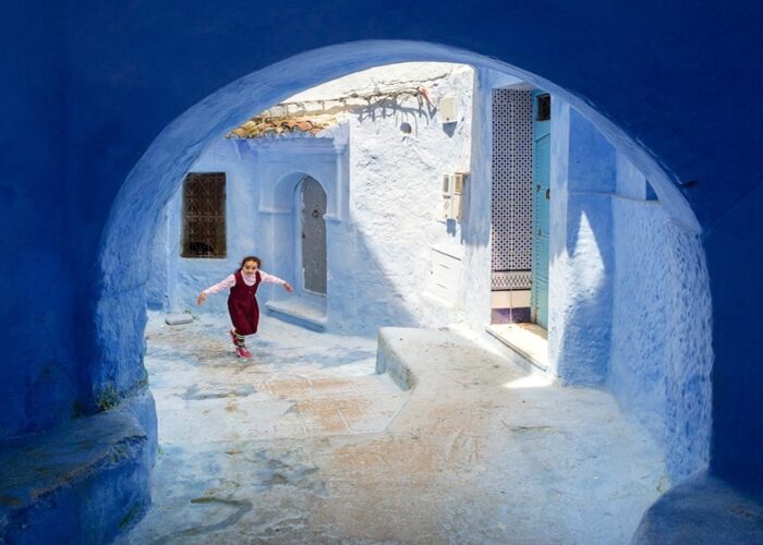 Una niña camina por calles azules durante el viaje de 2 días de Tánger a Chefchaouen.