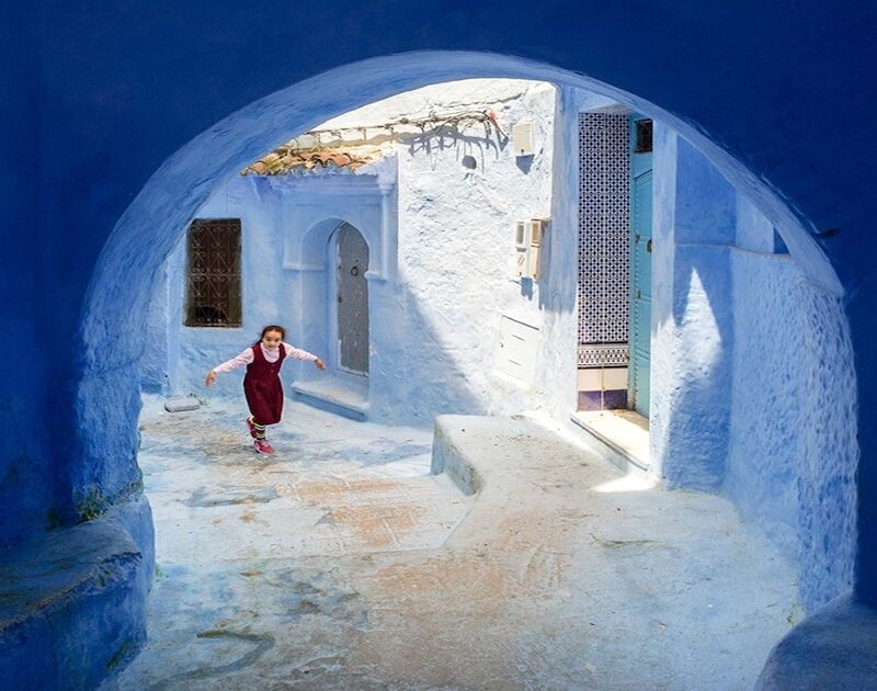 Una niña camina por calles azules durante el viaje de 2 días de Tánger a Chefchaouen.