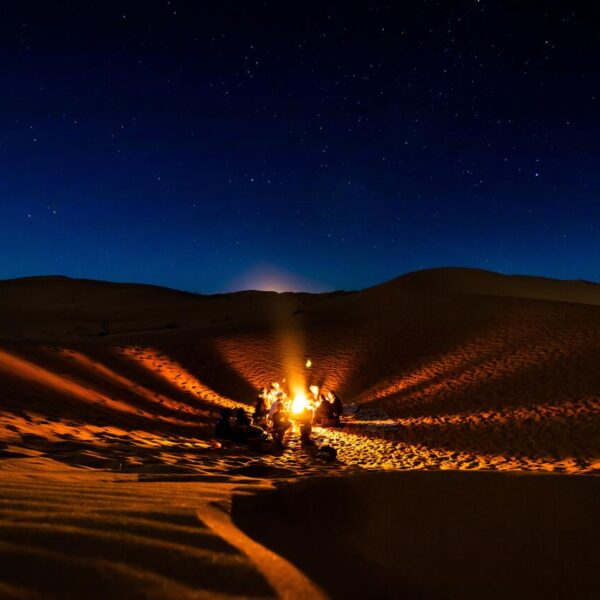 Gente alrededor de la hoguera por la noche en el desierto de Merzouga.