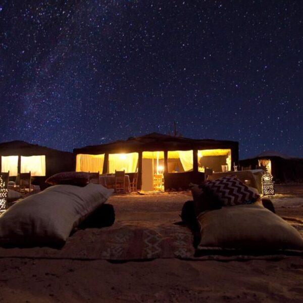 Un campamento en el desierto de Merzouga por la noche bajo las estrellas.