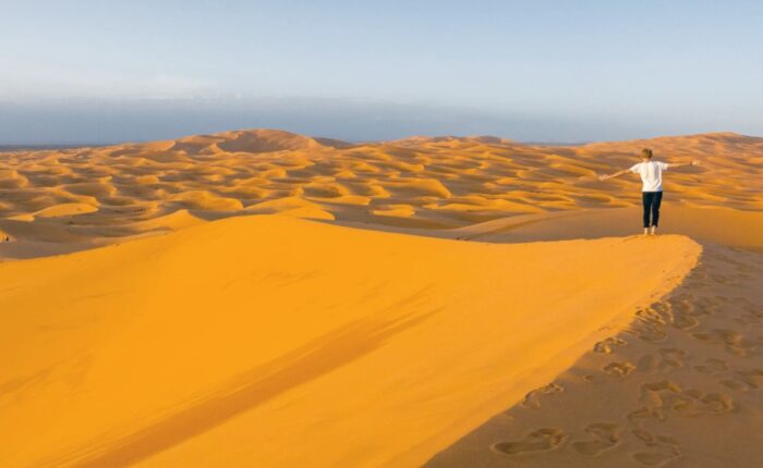 Un hombre camina por el desierto sahariano de Merzouga durante el viaje de 3 días desde Agadir.