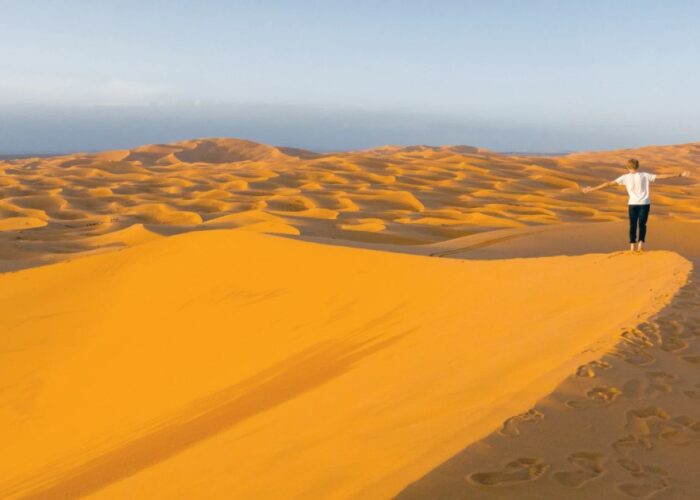 Un uomo che cammina nel deserto del Sahara di Merzouga durante il tour di 3 giorni da Agadir.