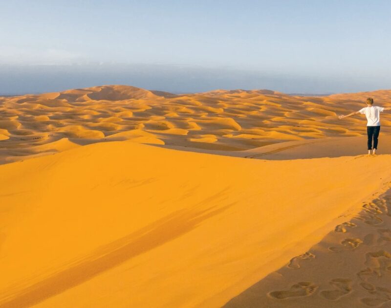 Un hombre camina por el desierto sahariano de Merzouga durante el viaje de 3 días desde Agadir.