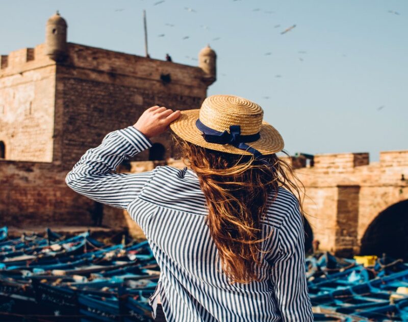 Una mujer con sombrero en el puerto durante la excursión de un día de Marrakech a Essaouira.