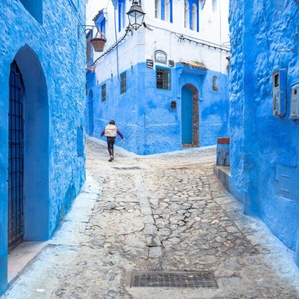 Un ragazzo che cammina per le strade blu di Chefchaouen.