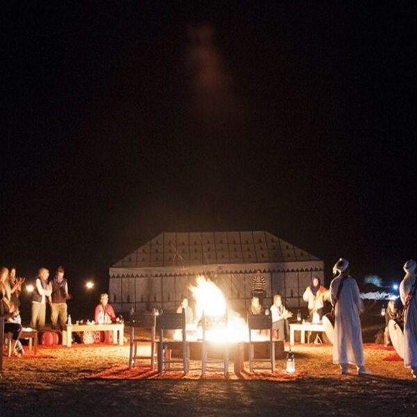 Tourists enjoy the desert night in Merzouga around the campfire.